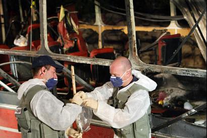 Police forensics experts work at the scene of a bus bombing in the northern Israeli city of Haifa, Wednesday, March 5, 2003. A suicide bomber blew up aboard a crowded bus in Haifa Wednesday killing at least 15, wounding dozens and ending a two-month lull in suicide bombings in Israel, offficials said. (AP Photo/Brennan Linsley)